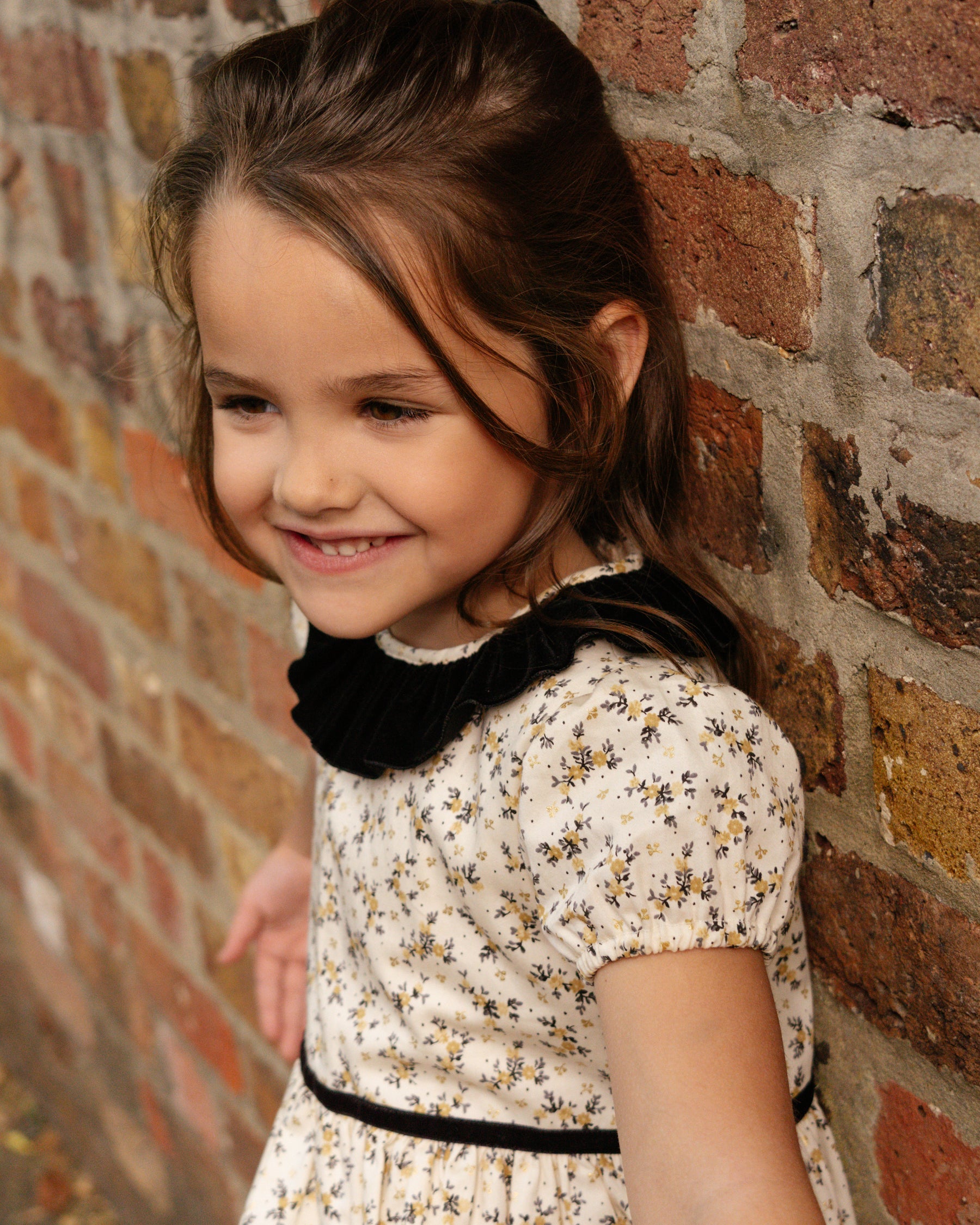 Young girl smiling against a brick wall
