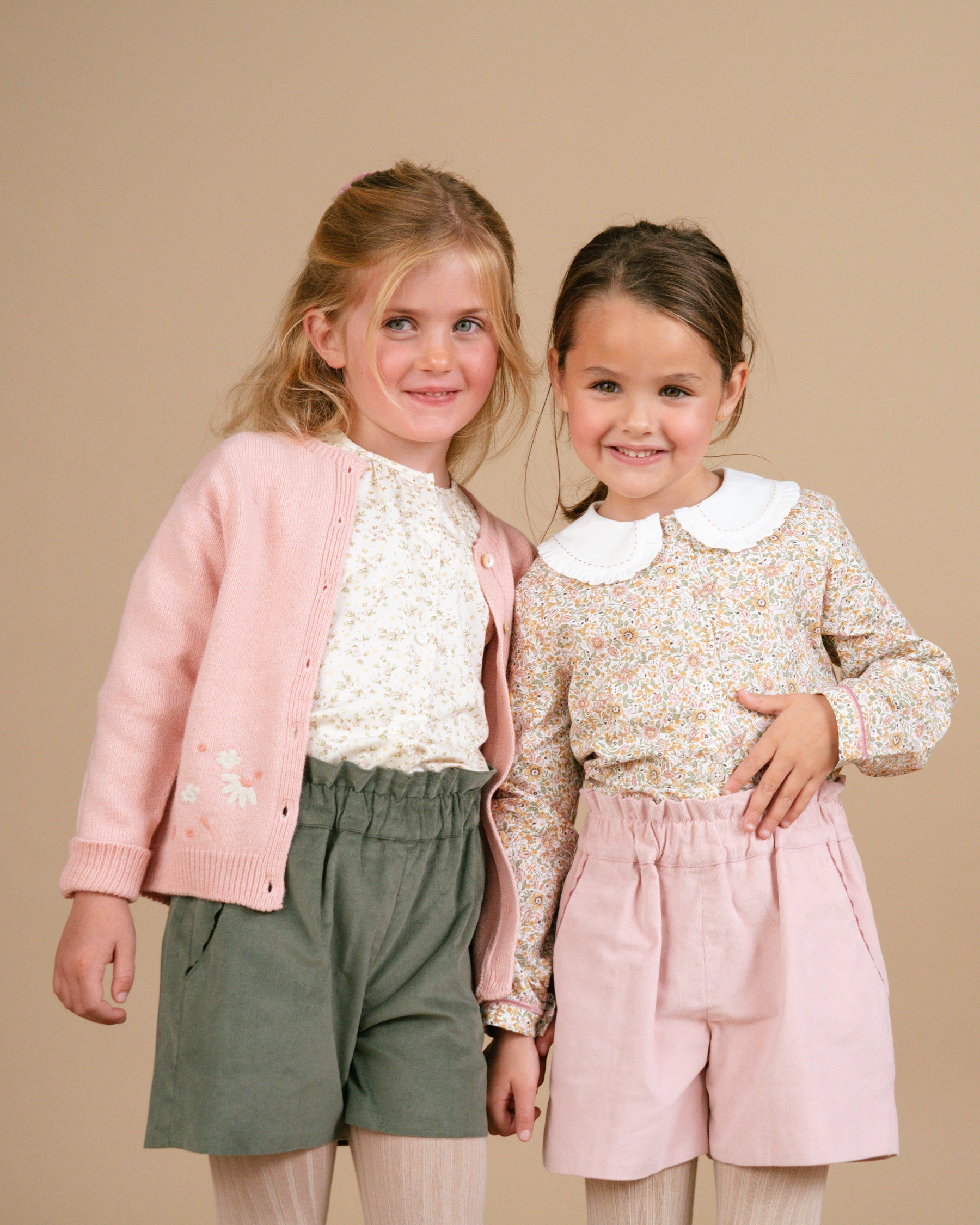 Des filles portant un short, un tee-shirt à motif floral et un cardigan rose