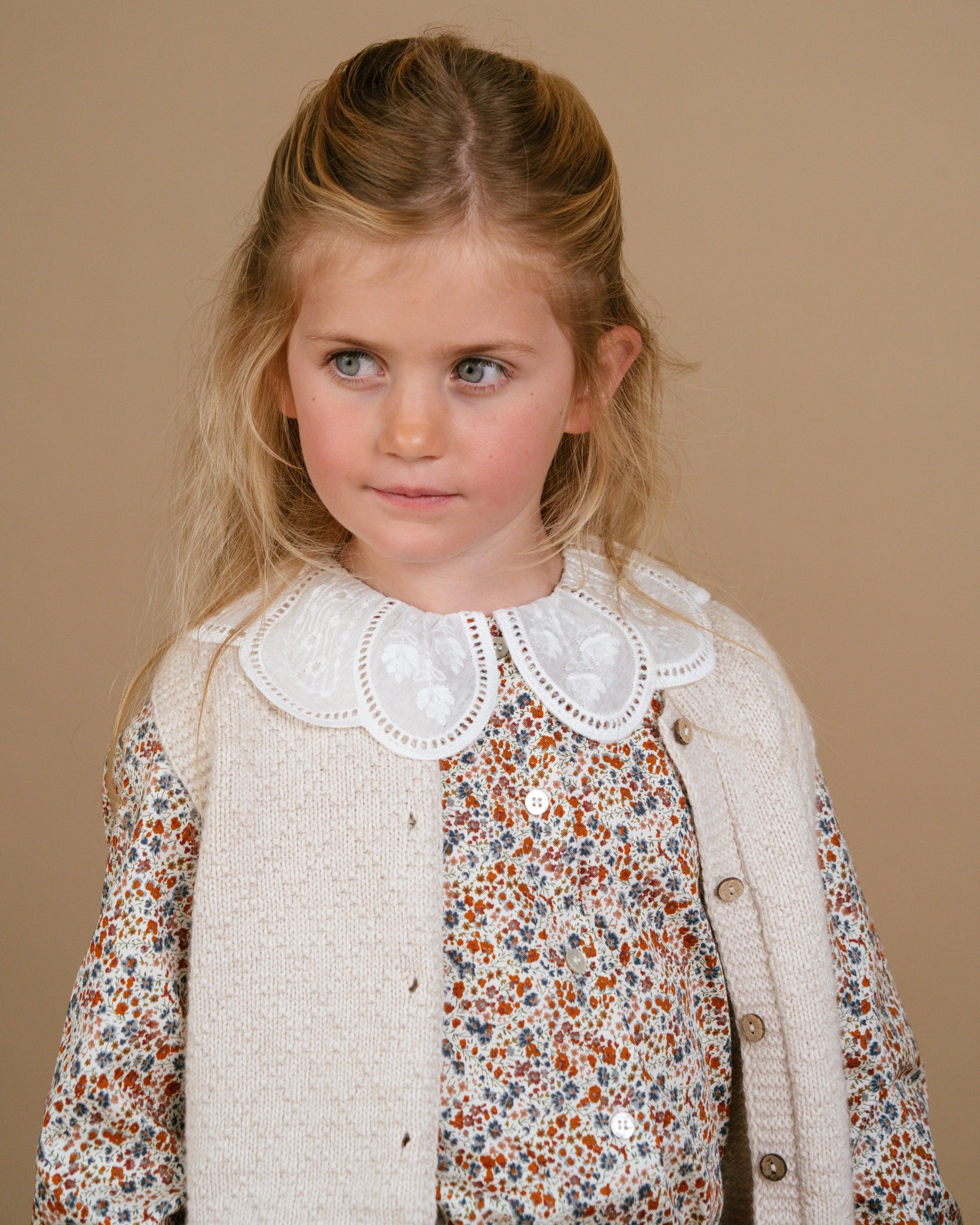 Girl wearing a beige sleeveless knit vest with buttons