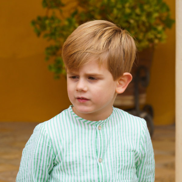 Young boy wearing a green and white striped shirt outdoors.