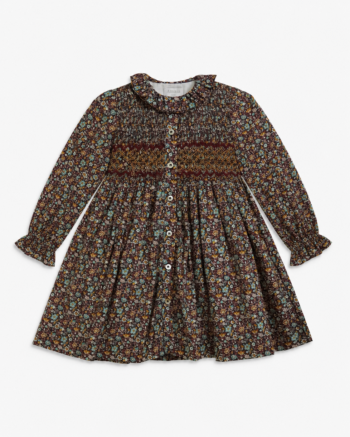 A long-sleeve children's dress with a dense multicolor floral print on a dark brown background, featuring a smocked waist and button-up front.