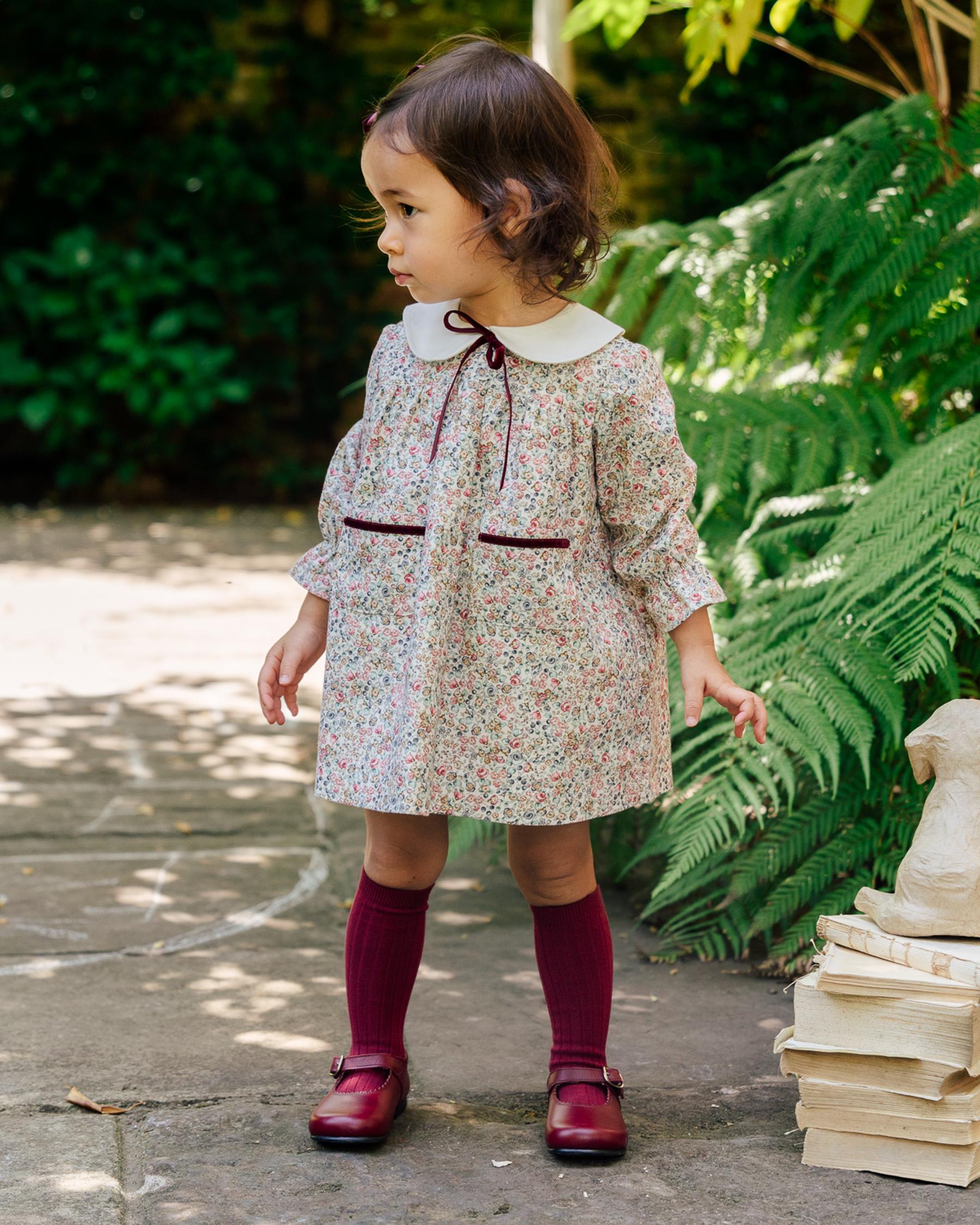 Baby girl wearing a dress and a burgundy leather dress