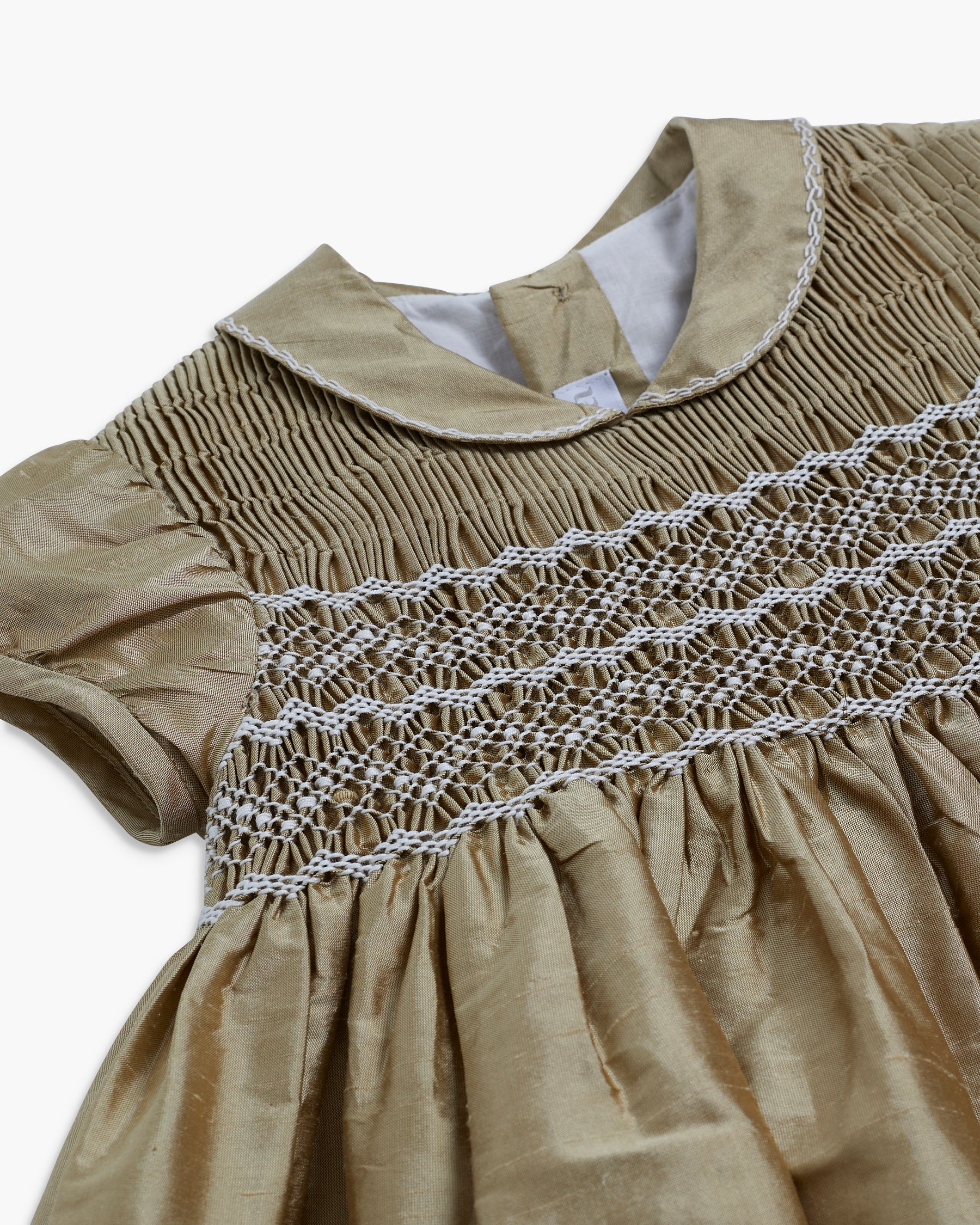 Beige dress with intricate white lace detailing on a white background