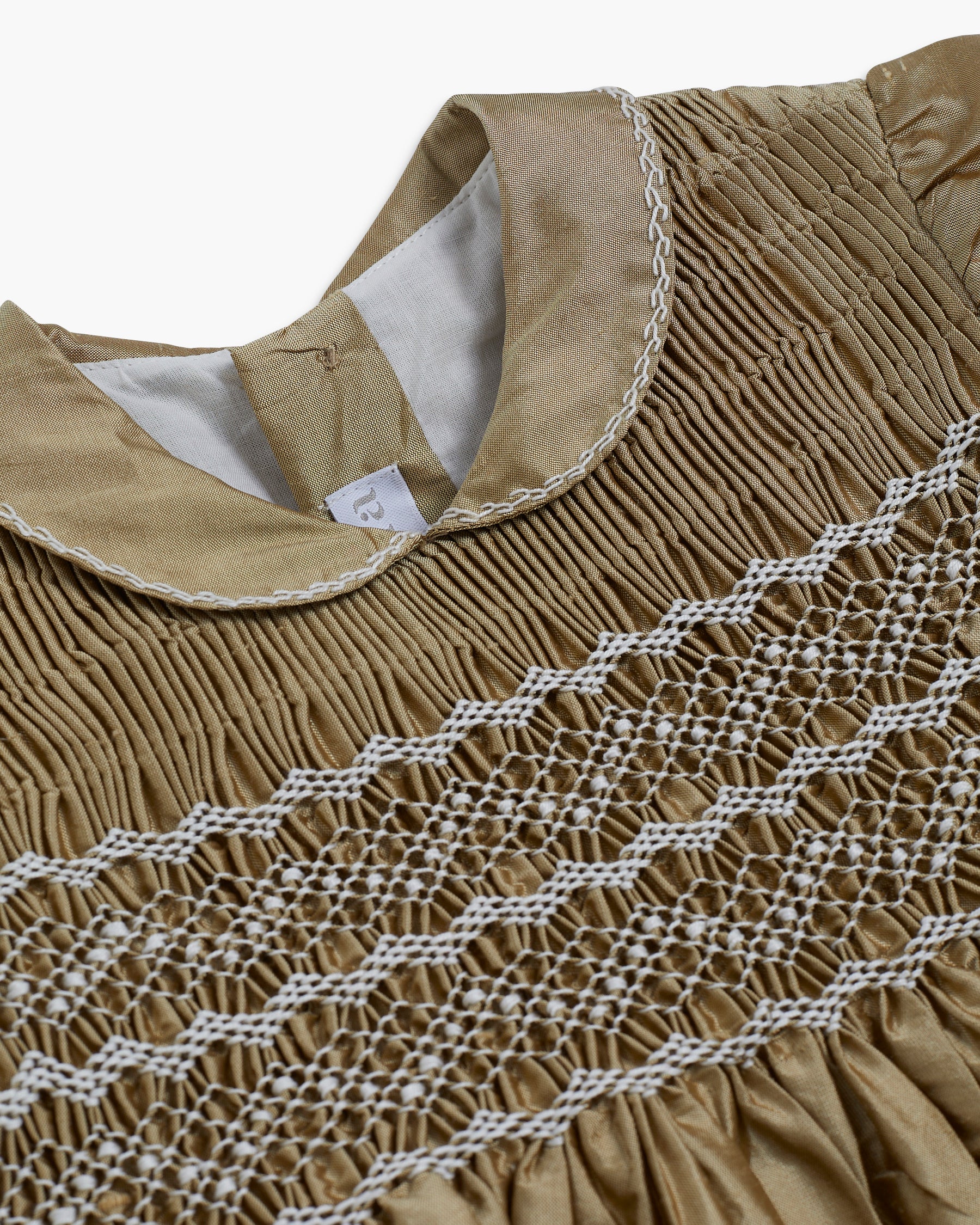 Close-up of a brown garment with intricate white stitching on a white background
