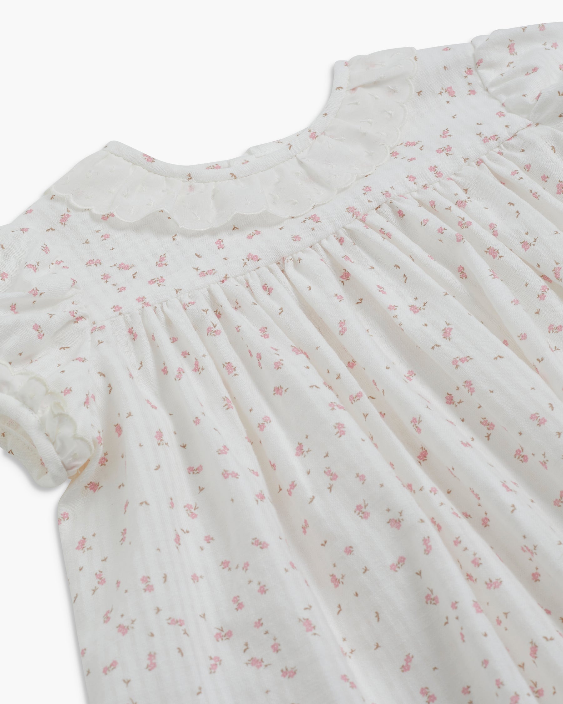 White dress with pink floral pattern on a white background