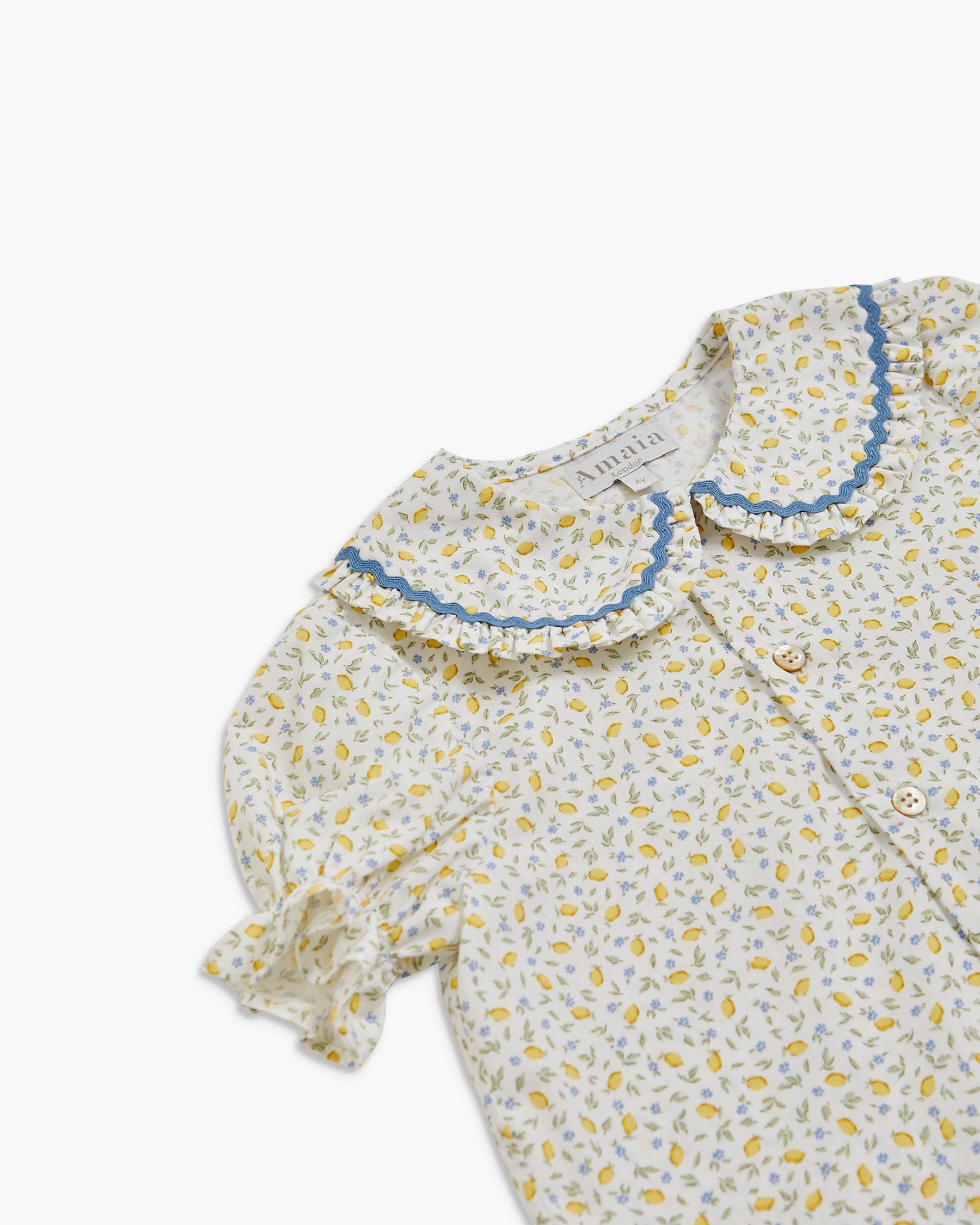 Floral patterned baby outfit with ruffled collar on a white background