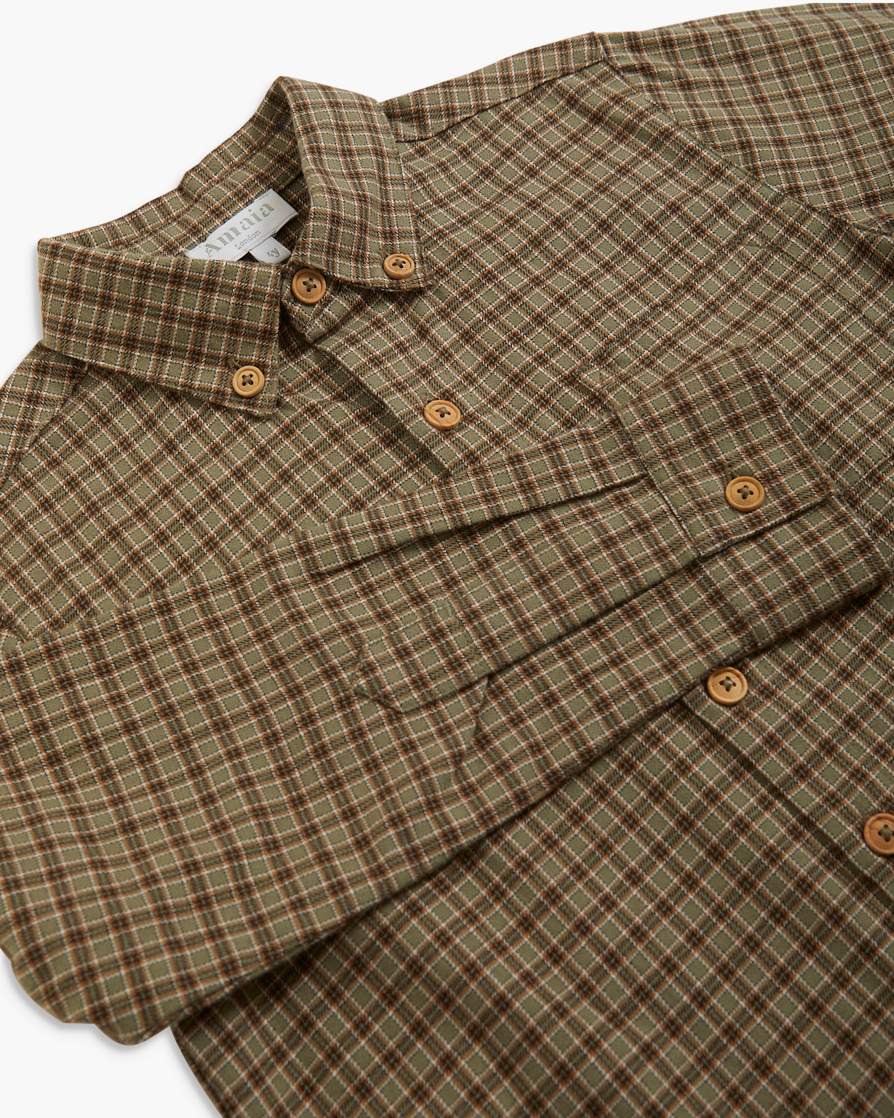 A close-up of a folded button-down shirt with a brown and beige plaid pattern, featuring brown buttons and a pointed collar.