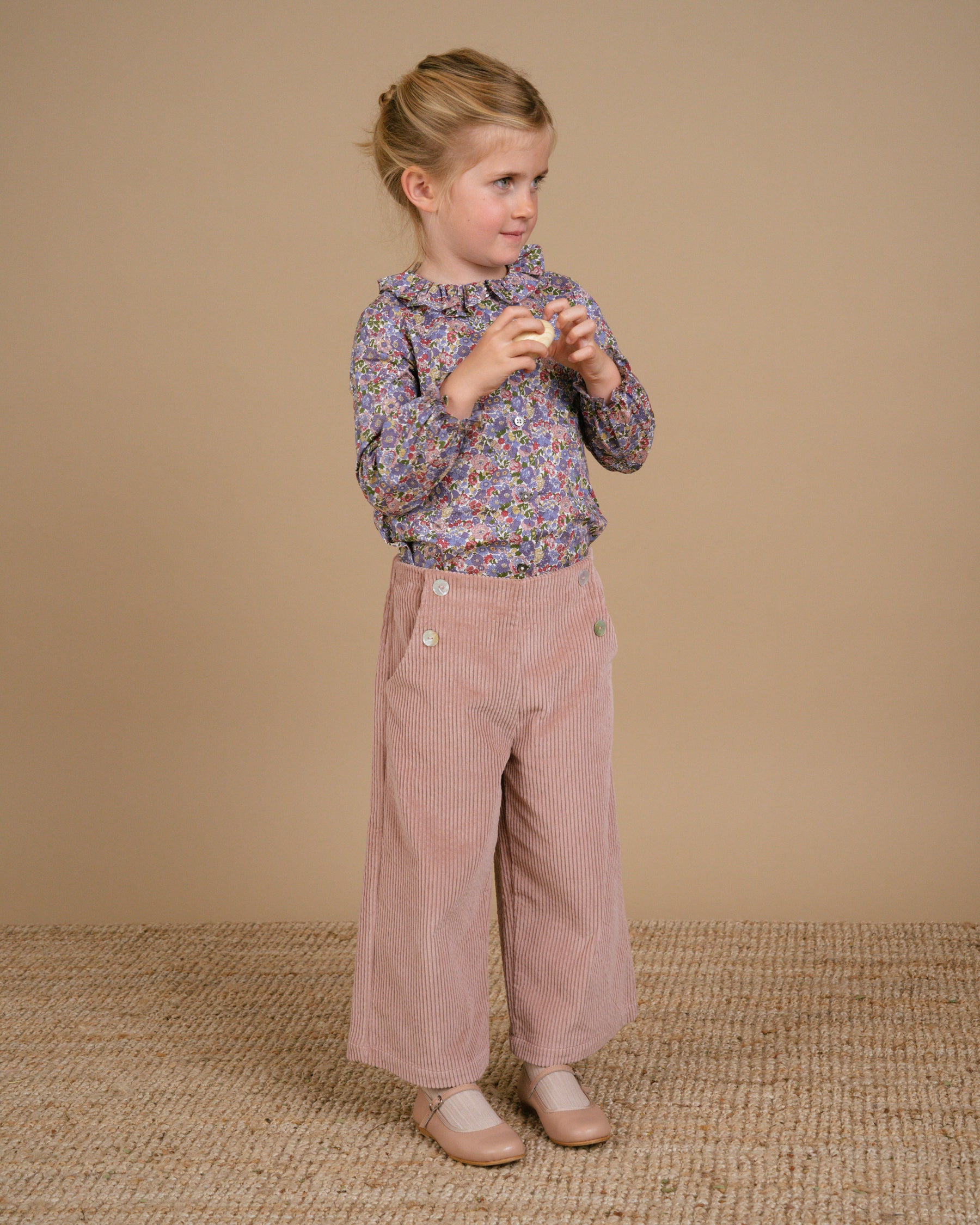 Girl wearing powder pink corduroy trousers and a floral t-shirt