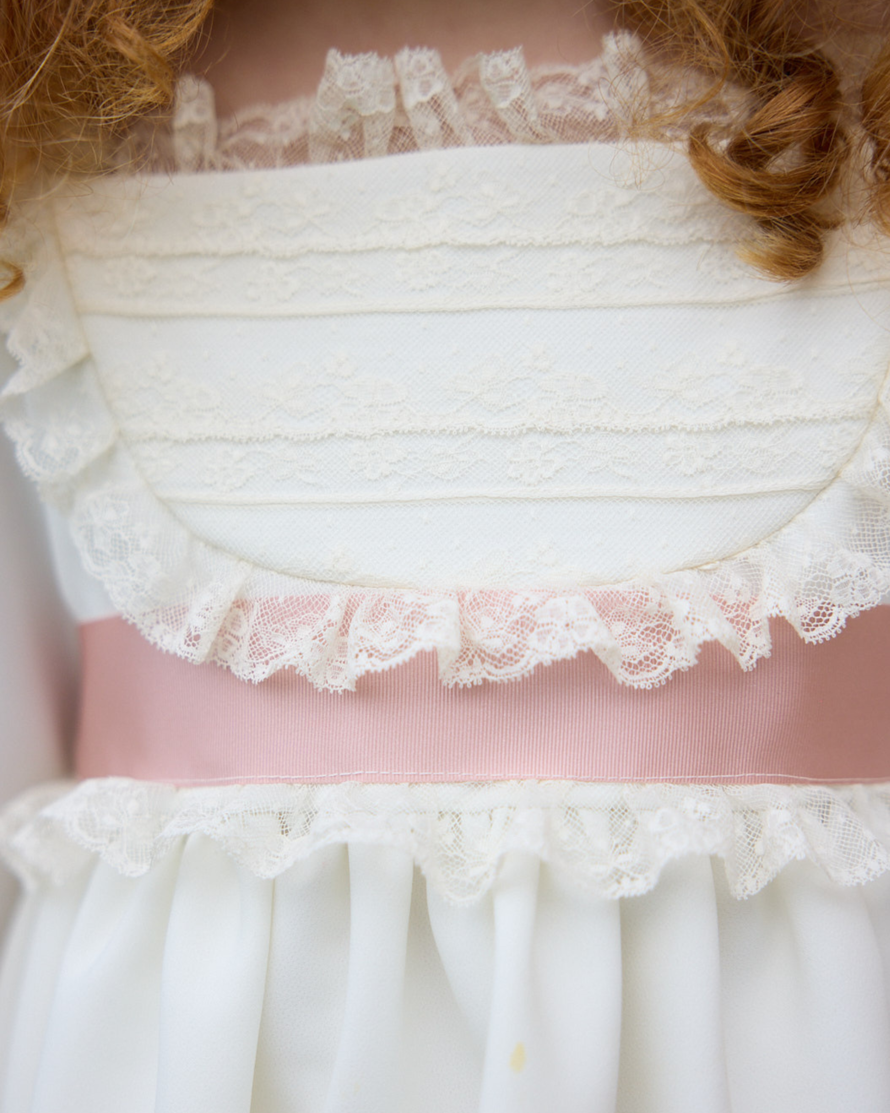 Close-up of a white lace top with a pink ribbon