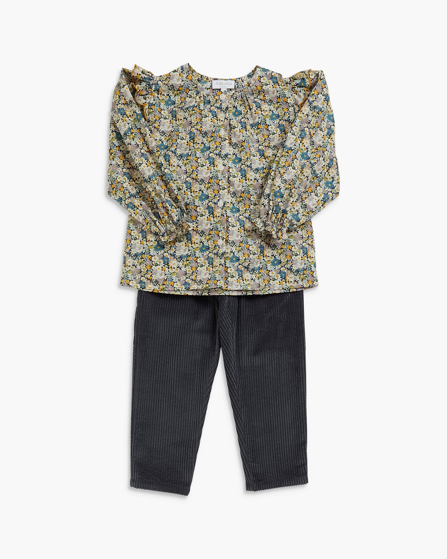 A children's two-piece outfit featuring a long-sleeve blouse with a dense yellow, green, and blue floral pattern on a light beige base, paired with dark charcoal gray ribbed trousers, shown flat on a light gray background.