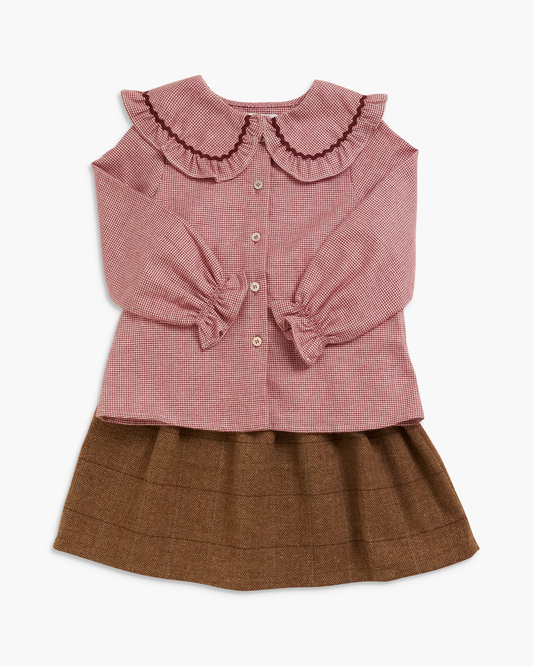 A children's two-piece outfit featuring a dusty rose pink gingham long-sleeve blouse with a ruffled Peter Pan collar and button front, paired with a brown pleated skirt, shown on a light gray background.