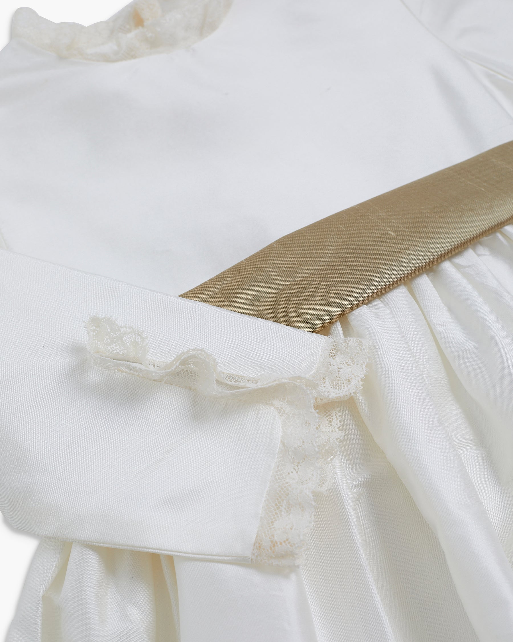 Close-up of a white dress with lace details on a white background