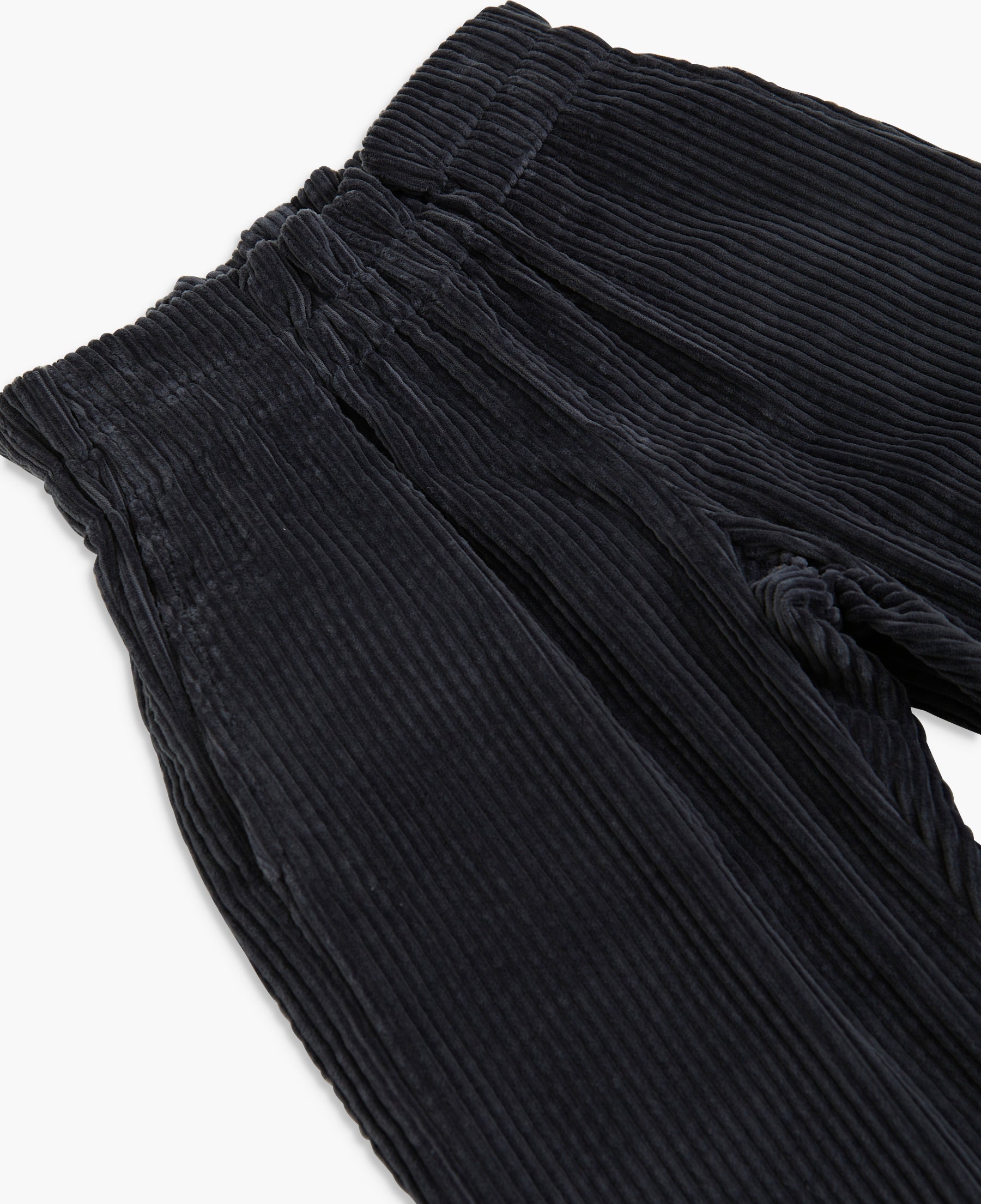 Close-up of black corduroy trousers showing the ribbed texture and elastic waistband on a white background.