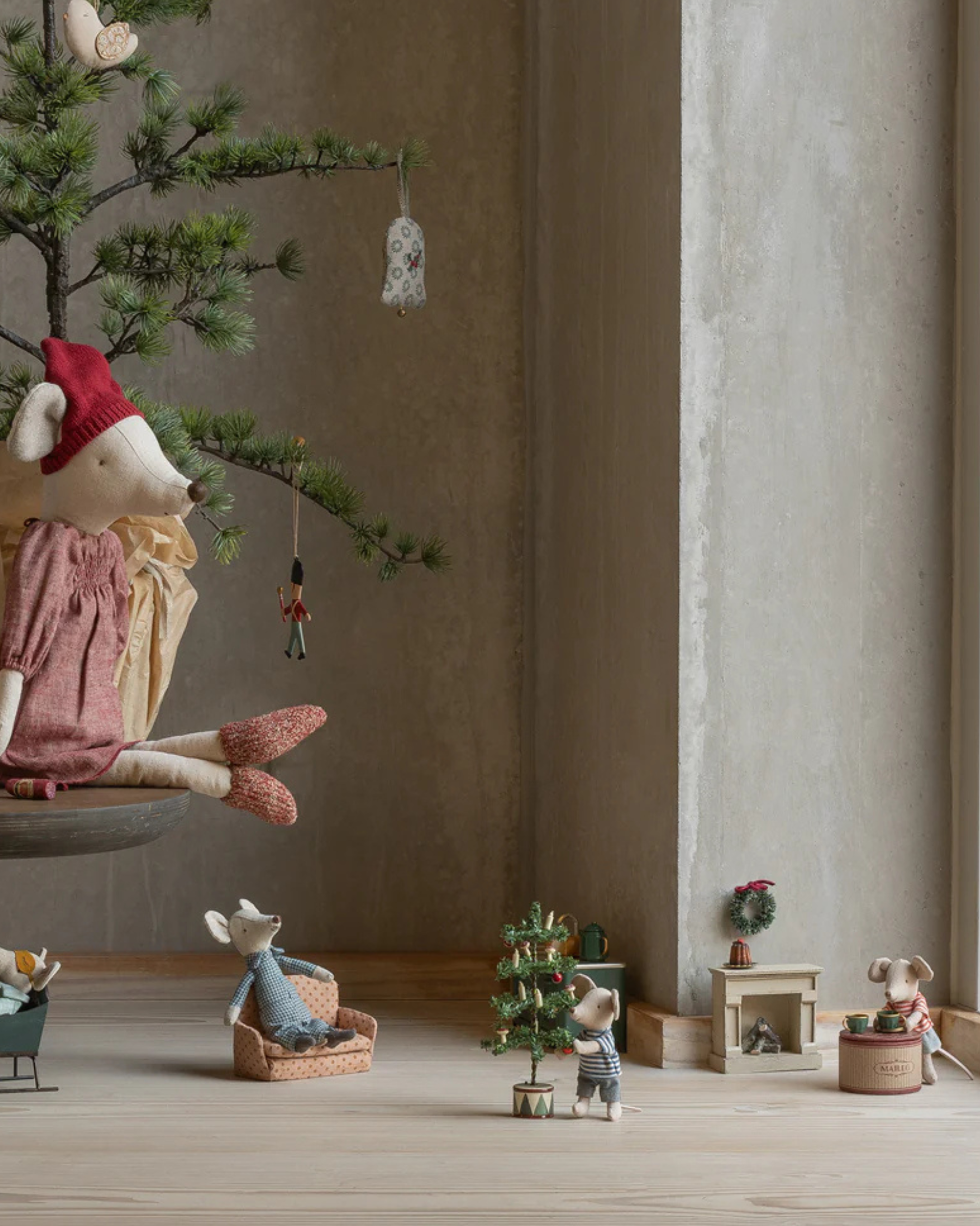 Miniature Christmas scene with toy figures and a small tree on a wooden floor.