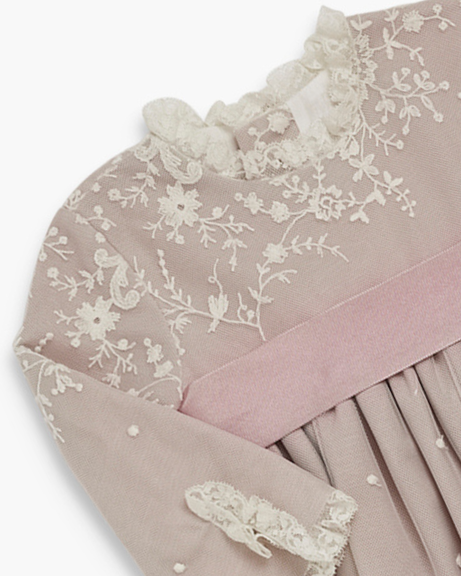 Delicate lace fabric with floral patterns on a light pink background