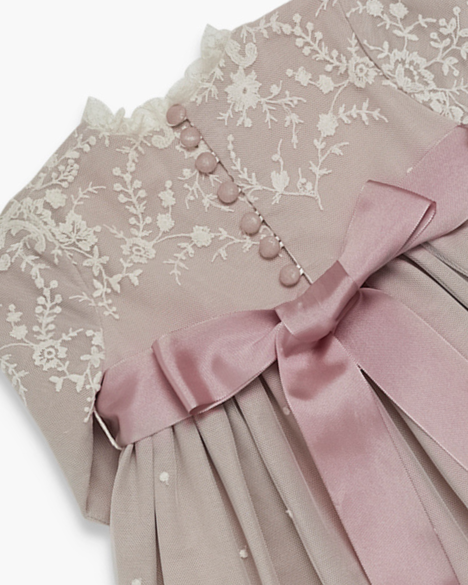 Pink dress with floral embroidery and a large bow on a white background