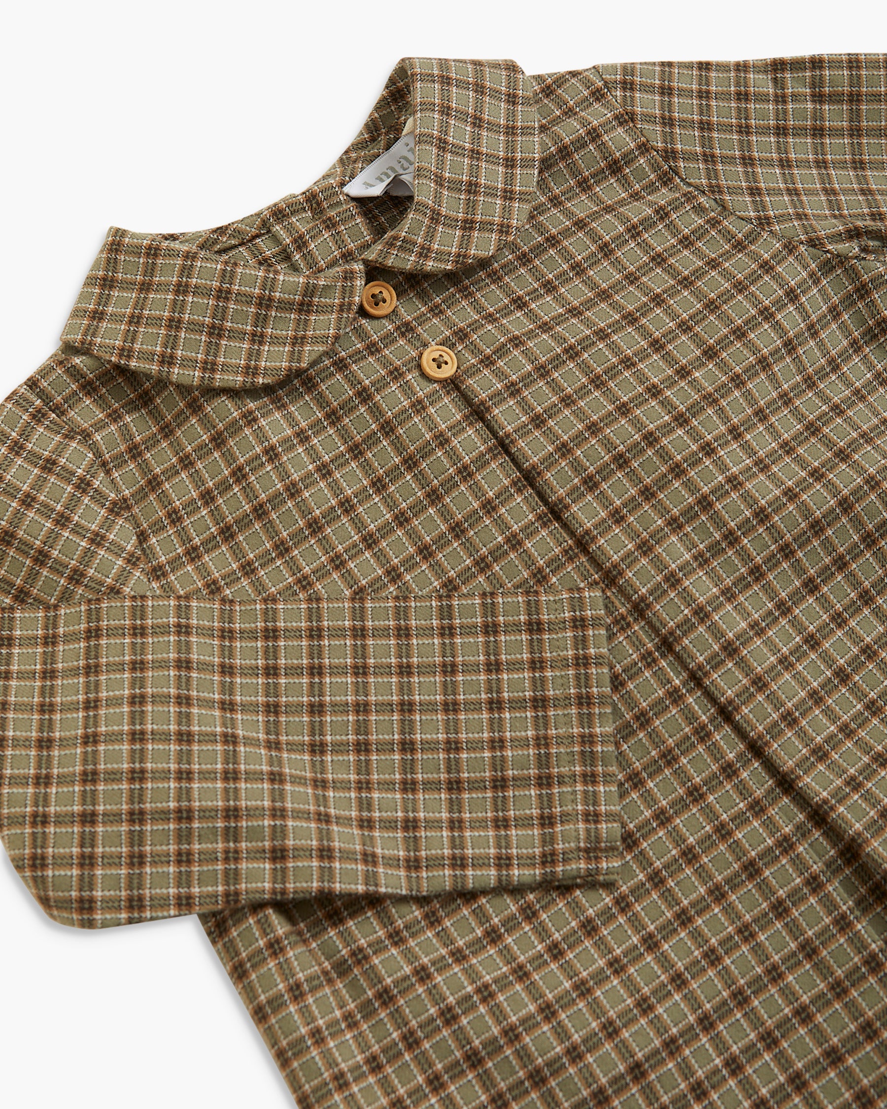 A close-up of a children's long-sleeve collared shirt with a brown and beige plaid pattern, featuring two wooden buttons on the collar.