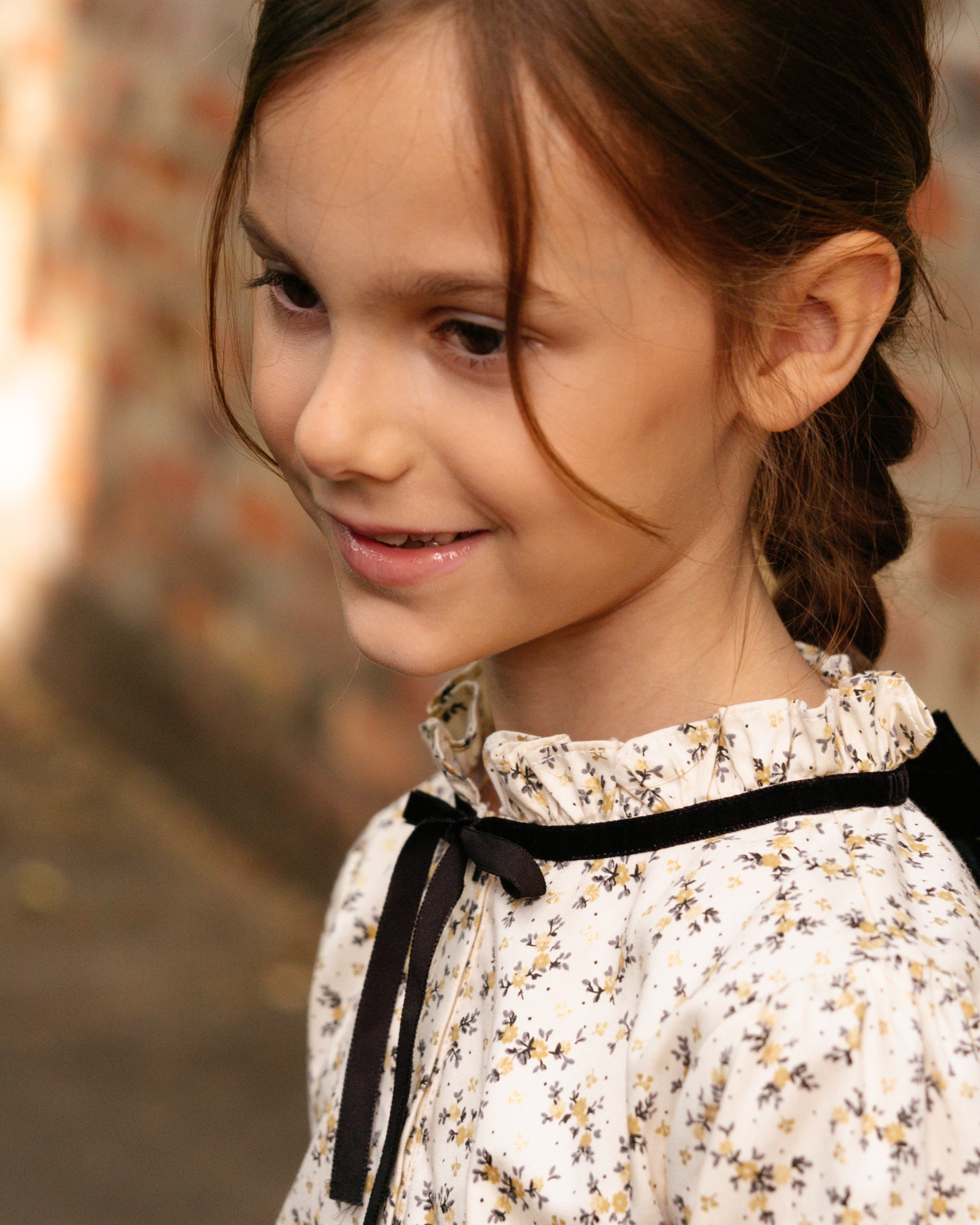 Young girl with a floral dress and black ribbon against a blurred background