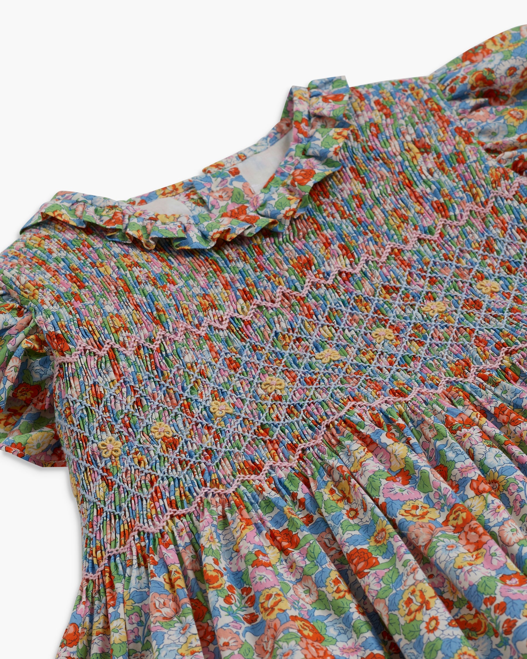 Colorful floral dress with smocked bodice on a white background