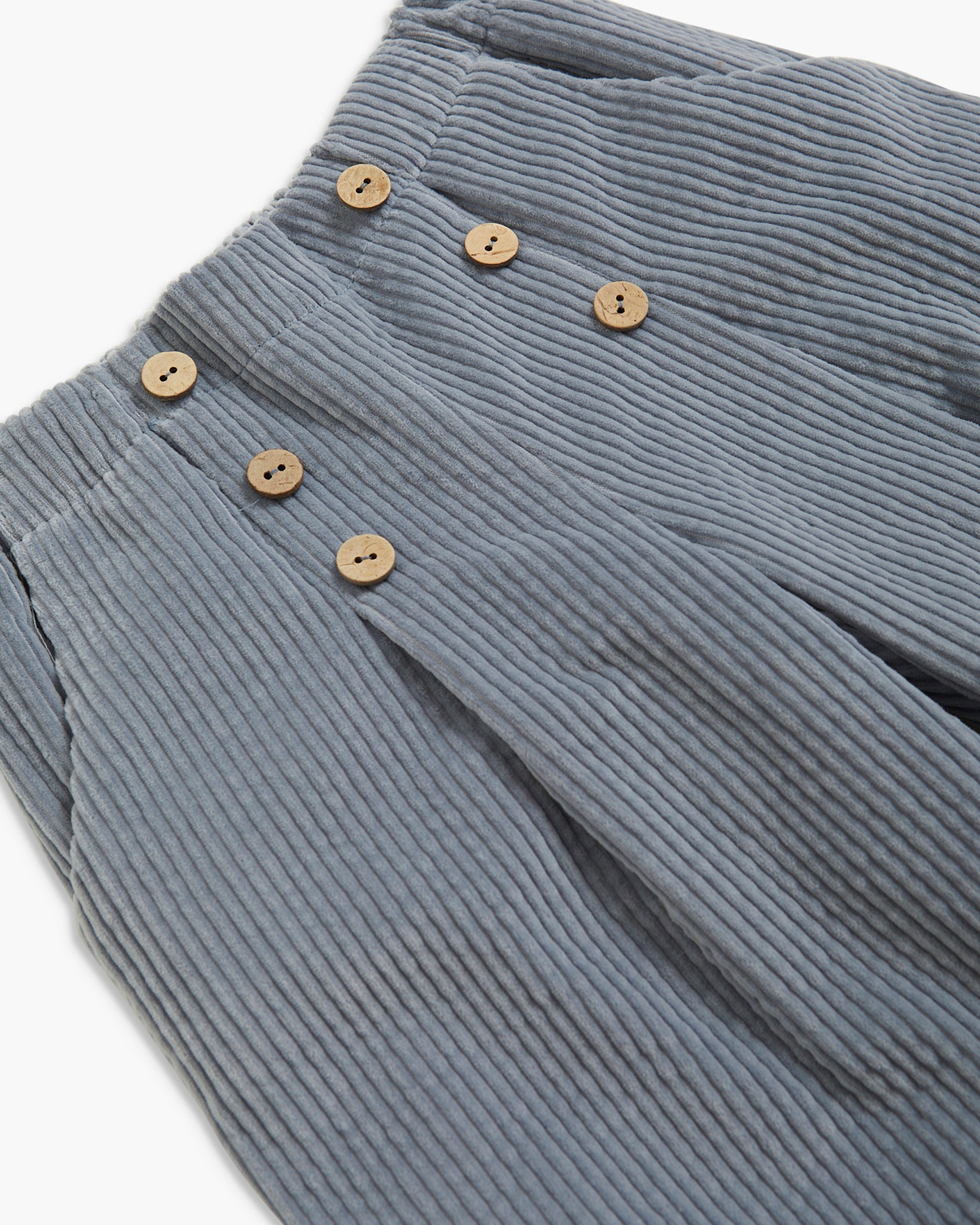 Close-up of a pair of ribbed corduroy trousers in a muted blue-gray color, featuring a double-breasted front with light brown buttons.
