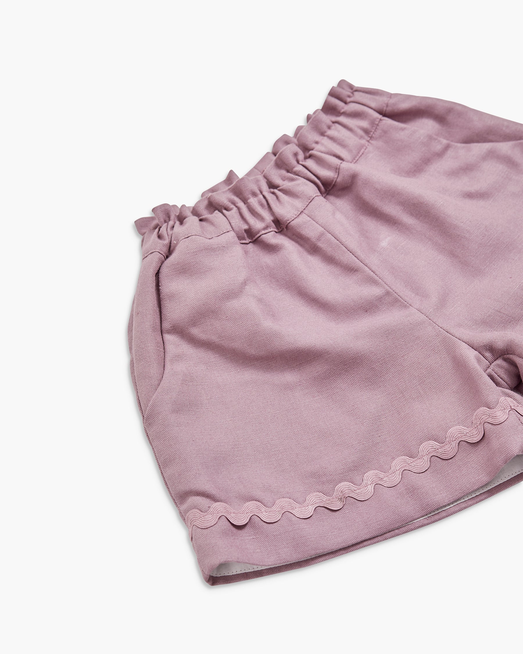 Pink shorts with scalloped hem on a white background