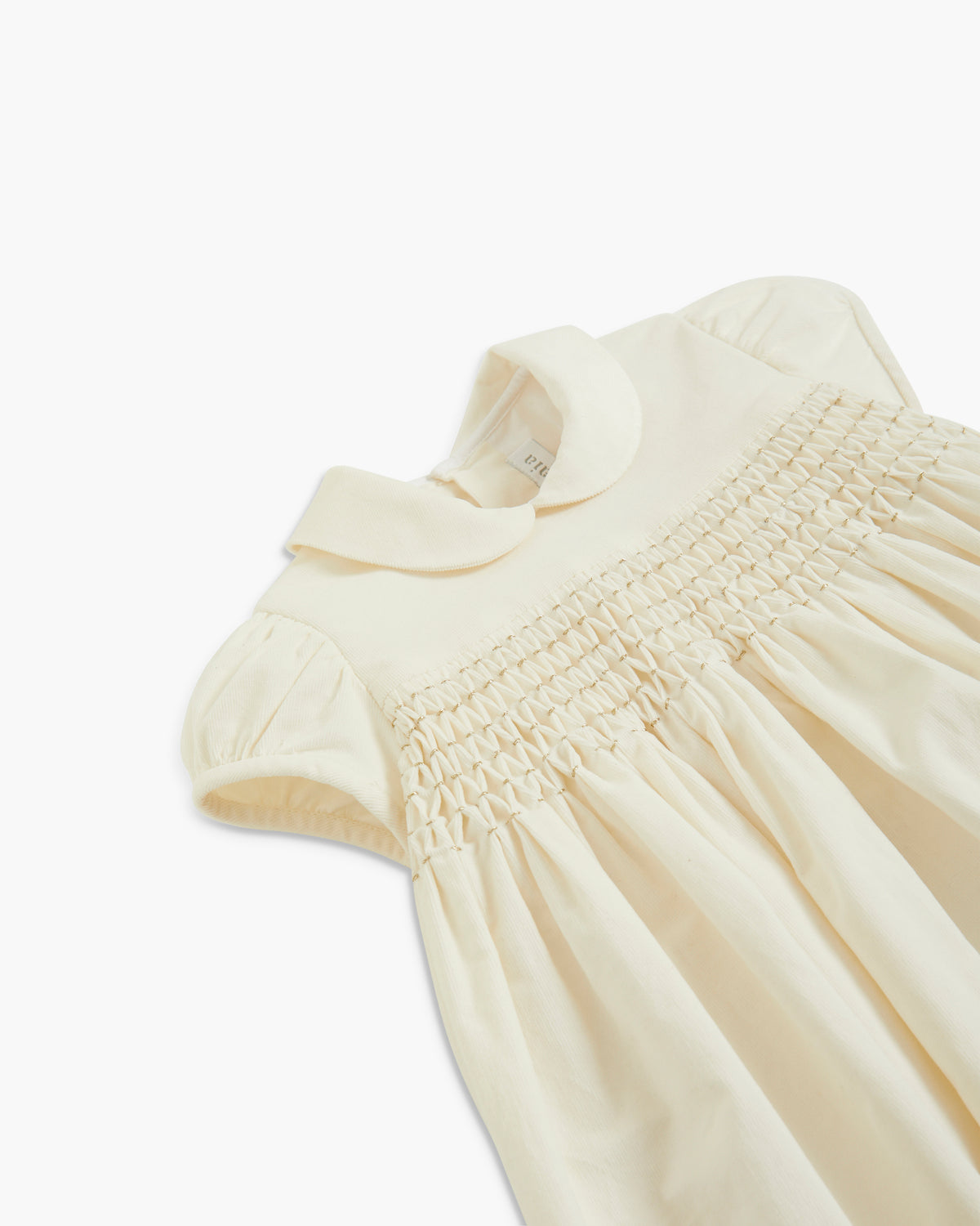 A close-up of a cream-colored baby dress with a smocked bodice and short puff sleeves, laid flat on a white background.