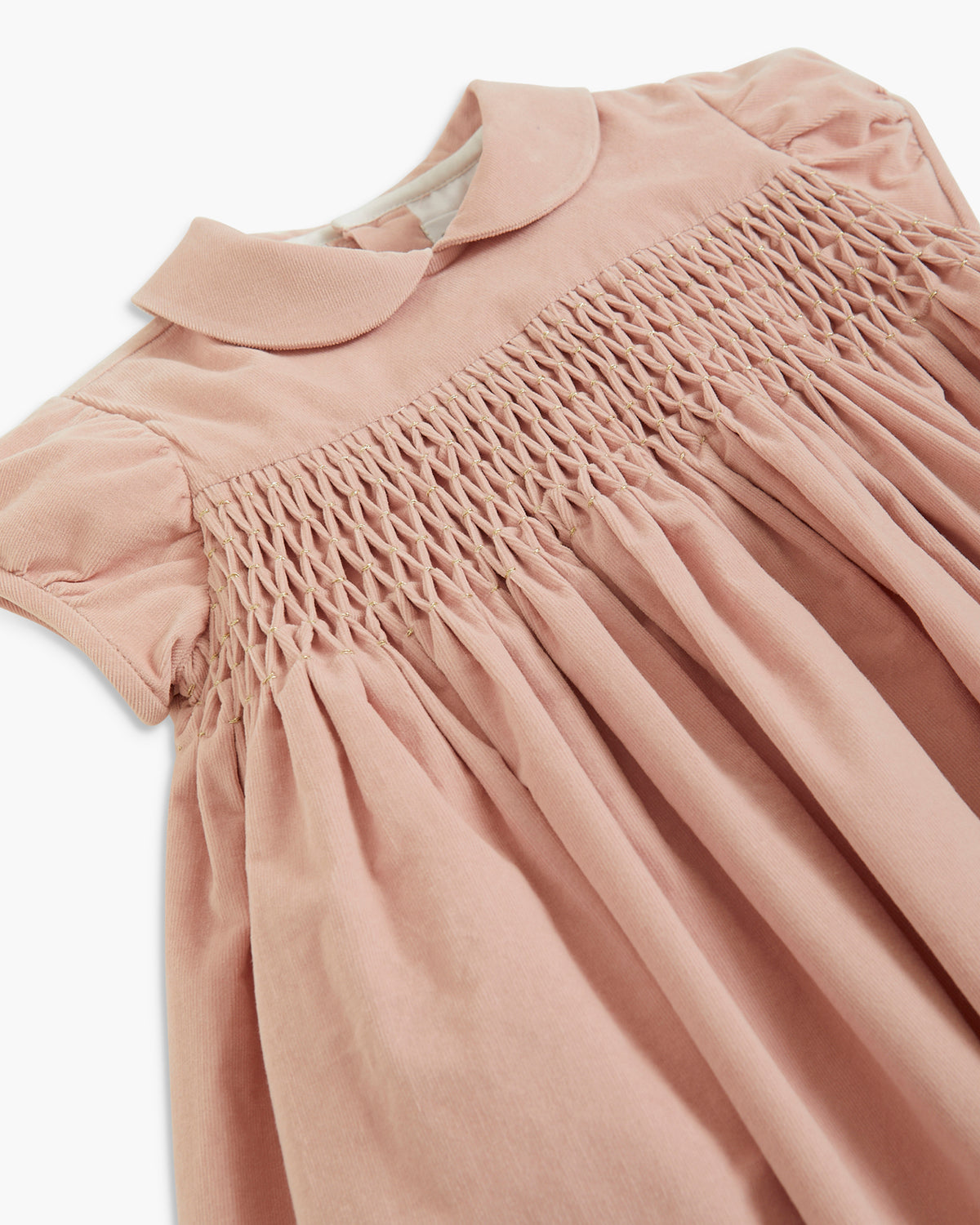 A close-up of a dusty pink children's dress featuring a Peter Pan collar, short puff sleeves, and delicate smocked detailing across the chest.