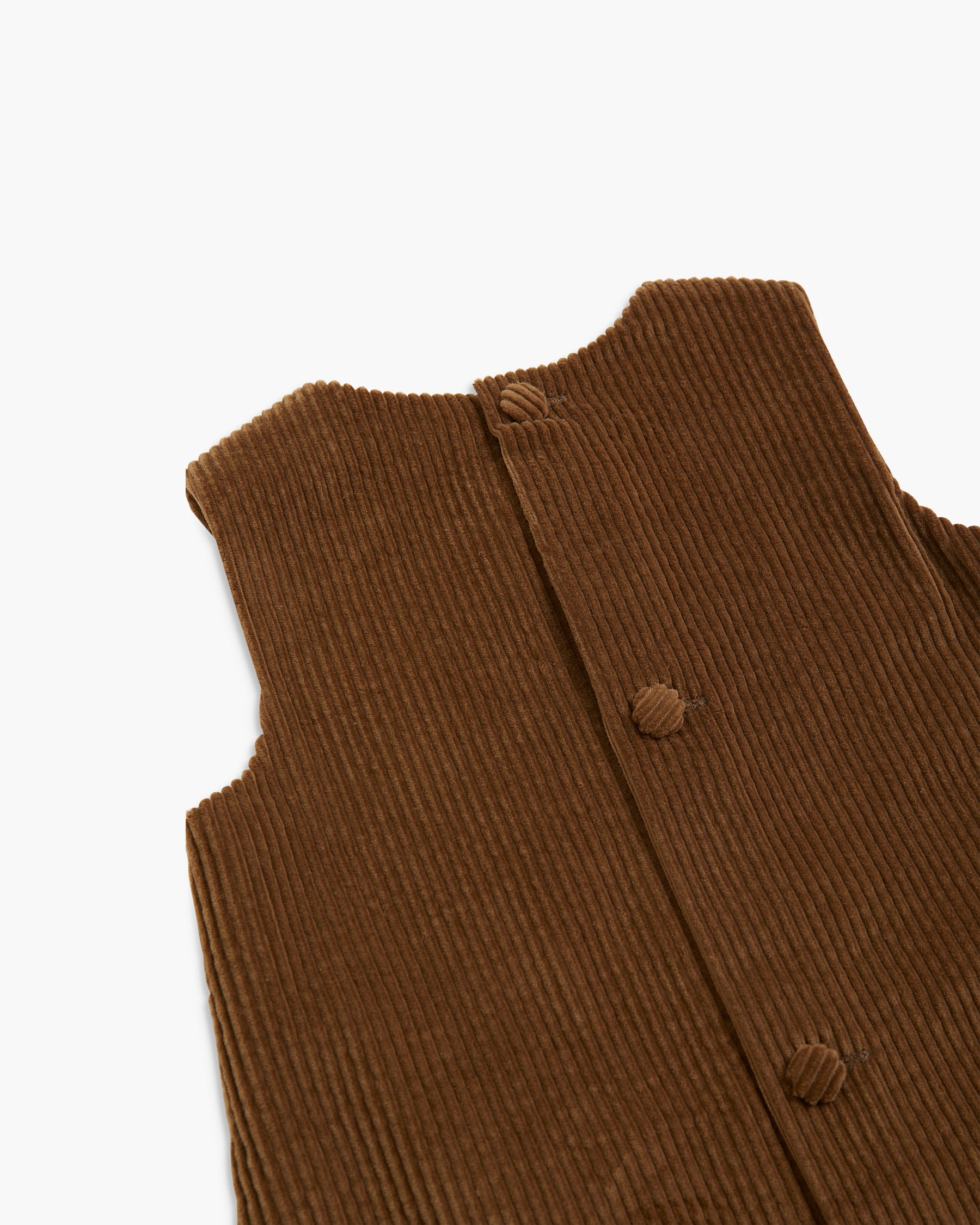Close-up of a brown ribbed corduroy garment, showing the back neckline and three matching fabric buttons on a plain white background.